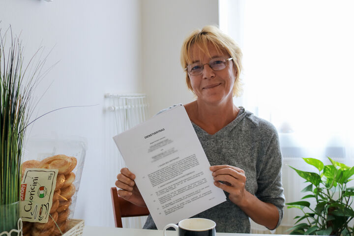 Frau H. zeigt stolz ihren Dienstvertrag.