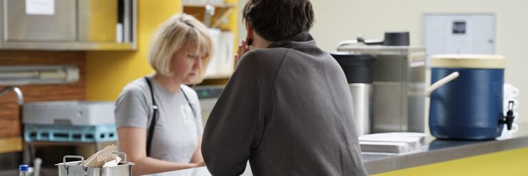 FSW Obdach Bereichsleiterin Barbara Trsek (l.) an der Theke des Obdach Josi. Die Besucher:innen des Schutzraums können die Abend und Nachtstunden in Sicherheit verbringen und bekommen eine basale Versorgung.​​ ​​​ (Bild: FSW)