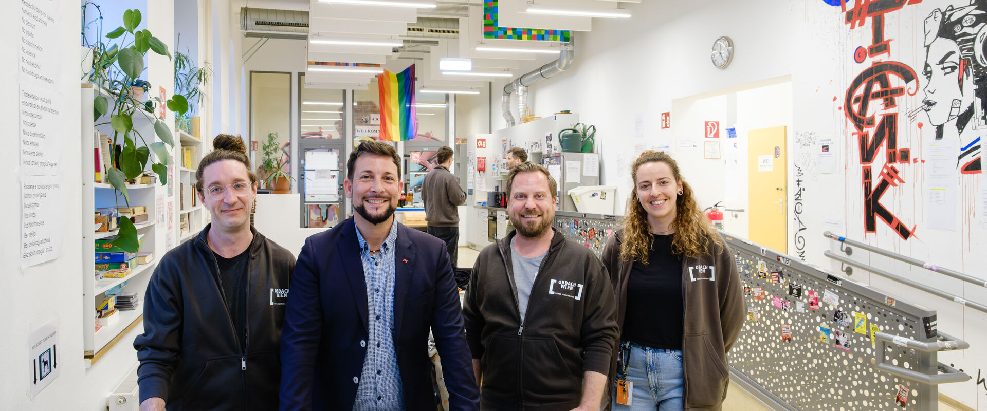 Das Obdach aXXept Team gemeinsam mit dem Bezirksvorsteher Markus Rumelhart im Tageszentrum Obdach aXXept vor einem Tischfußballtisch