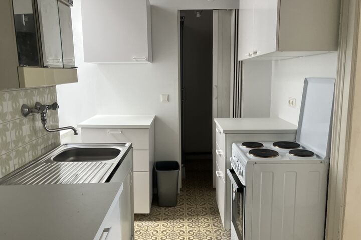 Vom Herd bis zum Bett: Im Obdach Dreyhausenstraße bietet eine Basisausstattung zum Wohnen. (Bild: FSW) Eine kleine, weiße Küche mit Herd, Abwasch und Küchenmöbeln.